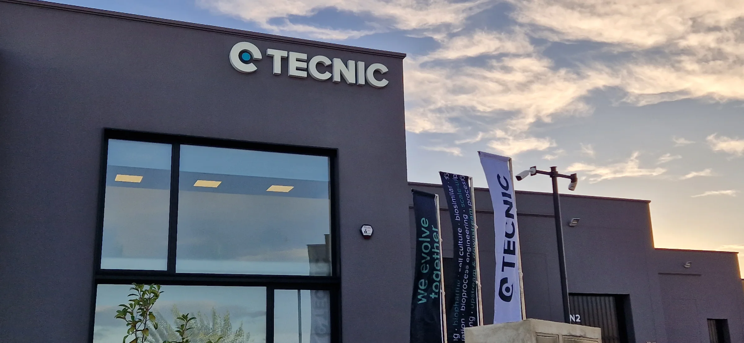 Façana de TECNIC amb rètols i banderes